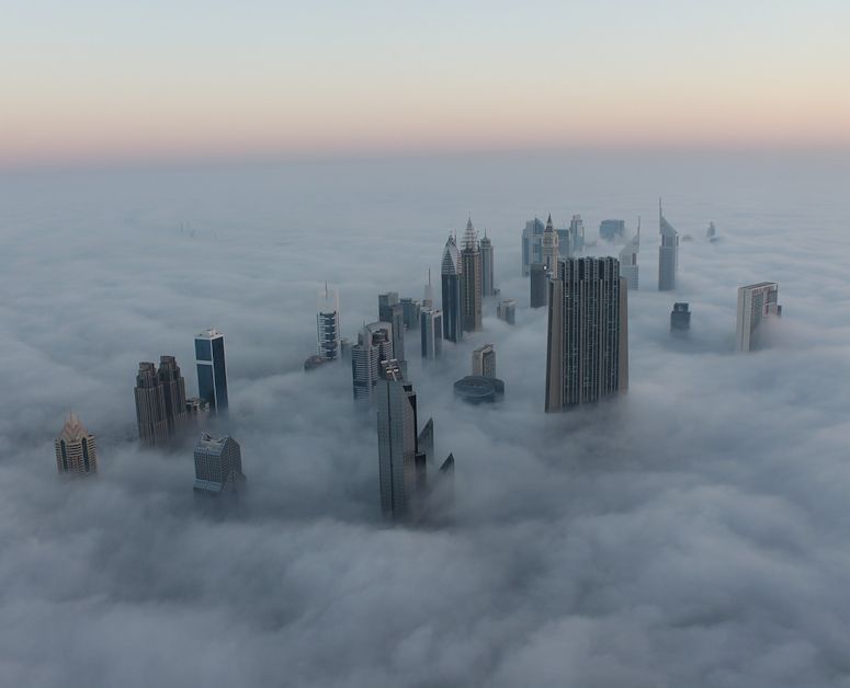 Hga skyskrapor i Dubai sticker upp genom moln eller dimma.