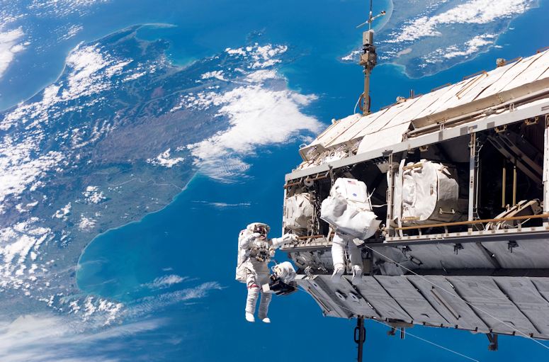 Christer Fuglesang och Robert Curbeam på rymdpromenad utanför Internationella rymdstationen, med jorden i bakgrunden