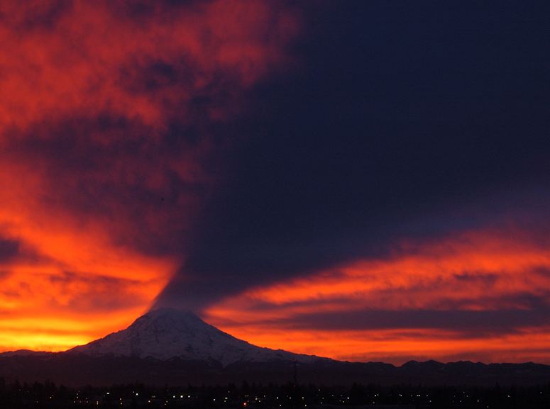 Mount Rainier kastar skugga p undersida av molnen