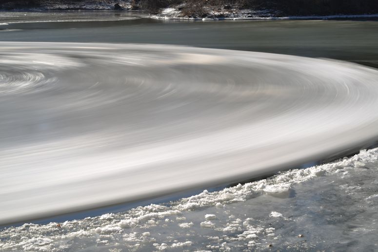 Snurrande skiva av is i strömmande vatten.