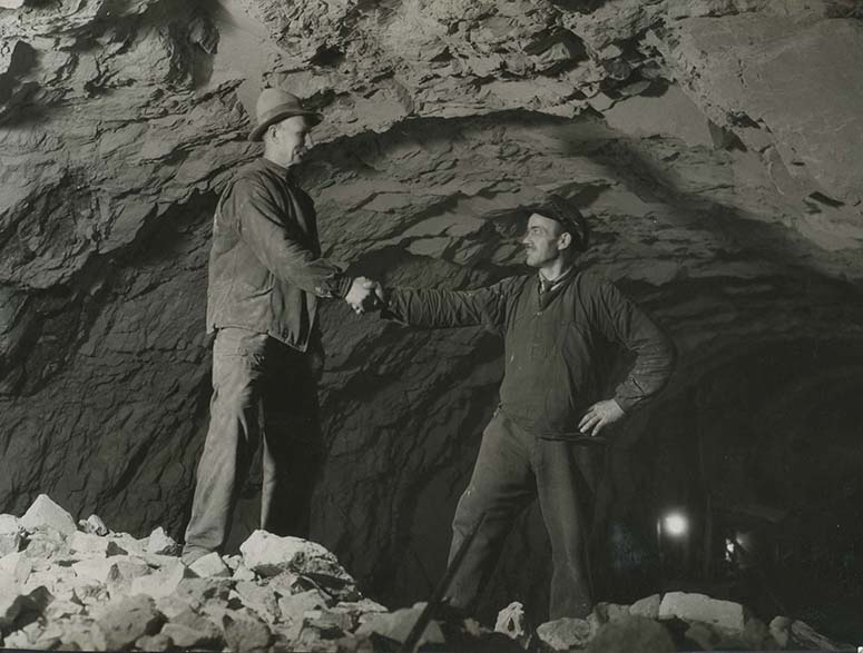 Två män skakar hand efter ha tunnlarna från Slussen respektive Södra Bantorget mötts 1932.