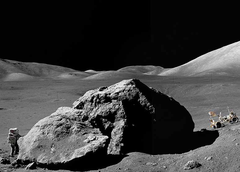 Astronaut Harrison Schmitt bredvid ett stort stenblock på månen