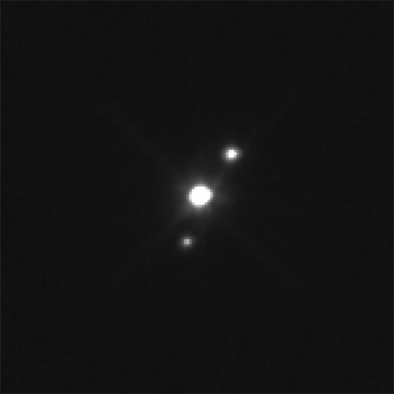 Haumea och dess två månar fotade 2015 av Hubbleteleskopet.